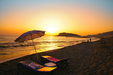 Beruhigende Meereslandschaft des abendlichen Sommerstrandes im Ferienort Alanya. Die untergehende Sonne vergoldete das Wasser des Mittelmeers. © Laura Pashkevich