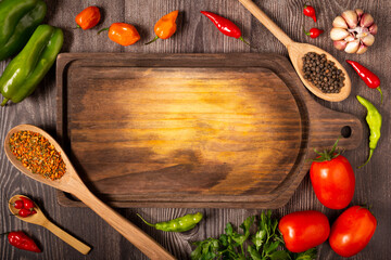 Empty cutting  board on the table with Ingredients for cooking. Tomatoes, various peppers, garlic and green peppers.