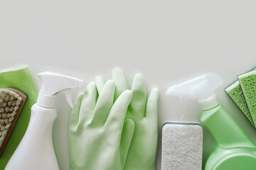 Green protective rubber gloves, rag, brush and sprayer with chemical detergent on white background. Housework and professional eco cleaning service supplies with copyspace.