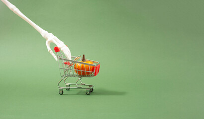 Halloween shopping all need even skeleton. Bizarre concept of skeleton hand and shopping cart. Pumpkin is all he needs.