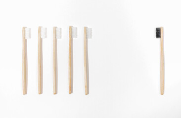 Row of white eco friendly natural bamboo toothbrushes against one black on white backdrop.