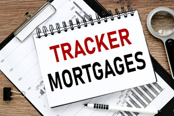 Tracker Mortgages, notepad on wood background near financial charts