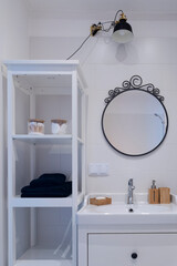 Modern interior of small bathroom with round mirror,stylish lamp and ceramic bathroom sink. Scandinavian design.