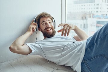 cute man lying near the window wearing headphones hipster