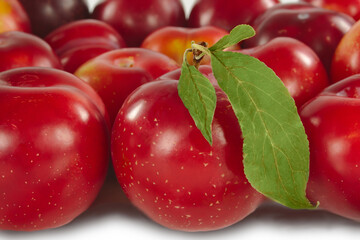 ripe fruit, red with a green leaf, glossy surface.