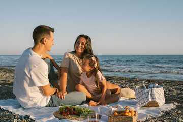 Summer family leisure picnic lunch with fruits by the seaside. Happy people eating healthy food on...