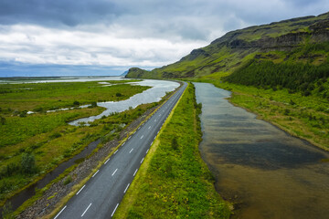 Obraz premium Iceland. Aerial view on mountain, field and river. Landscape in Iceland at the day time. View from drone. Summer. Cloudy weather. Fresh grass on field. Travel and vacation image
