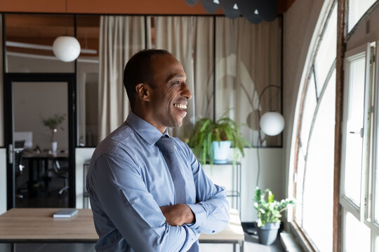 Side portrait of confident African American mature business man. Happy thoughtful middle aged leader, executive, director in formal clothes looking out of window, thinking over good future vision