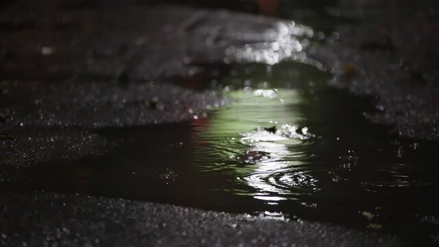 Night Rain Puddle On A Black Asphalt With Water Drops Falling Into It