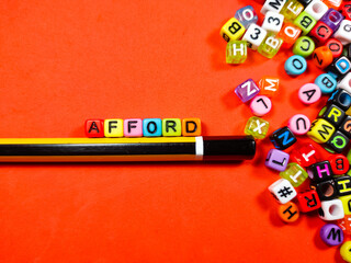 Colorful alphabet beads with text AFFORD and pencil on red background.