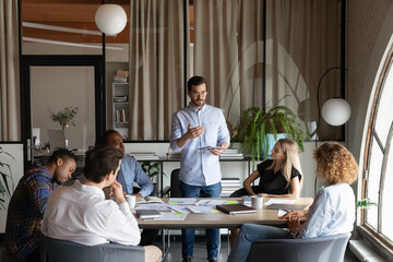 Confident business team leader speaking to employees at corporate meeting. Boss discussing sales...