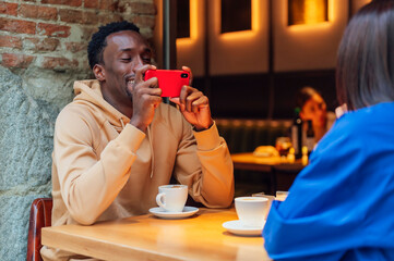 Man taking selfie with woman while sitting in cafe.