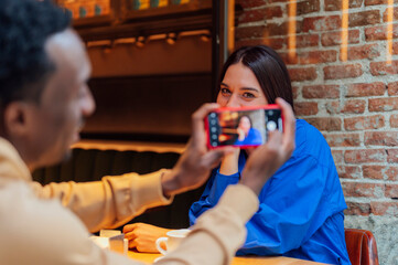 Cheerful man making selfie with his girlfriend in cafe