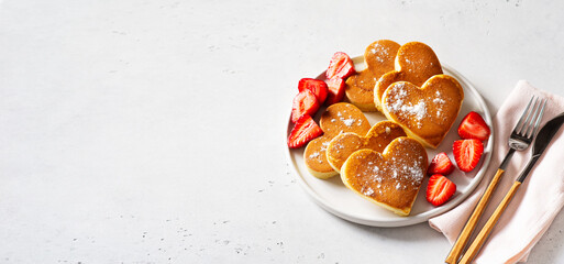 Heart pancakes with strawberry on plate with tableware