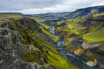 Woman hiker enjoying Highlands of Iceland. River Fossa stream in the Landmannalaugar canyon valley....