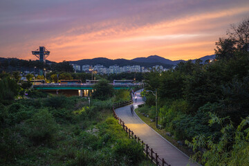 도심 속 하천의 분홍색 일몰과 산책로를 가로지르는 자전거 풍경