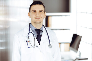 Male doctor standing straight in sunny clinic. Perfect medical service in hospital - 459277886