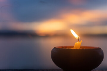Candle light fire lamp nearby abstract background river during sunset or sunrise in countryside. Melting candlestick in evening twilight. Religion abstract concept.