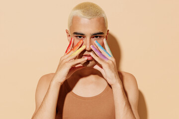 Young serious sexy fun blond latin gay man wear beige tank shirt posing with make up fingers...