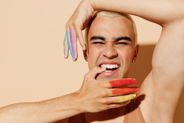 Young sexy cool fun blond latin gay man 20s with make up fingers painted in rainbow flag colors...