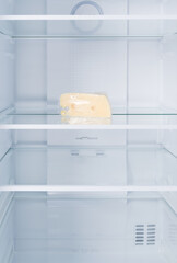 a piece of cheese, in the refrigerator on a glass shelf, on a white background