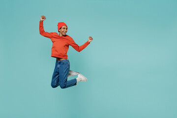 Fototapeta na wymiar Full body fun cool young smiling happy african american man 20s in orange shirt hat do winner gesture jump high isolated on plain pastel light blue background studio portrait People lifestyle concept