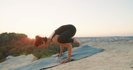 Full length view of the young flexible woman doing sport yoga exercise asana in beautiful mountains landscape on the sunrise