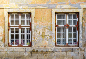 Old windows in stucco facade deteriorated by the passage of time.