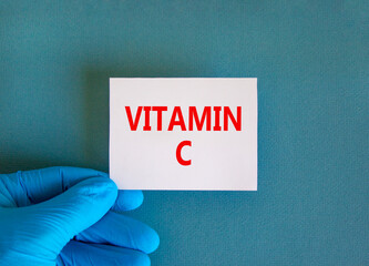 Vitamin C symbol. White note with words Vitamin C, beautiful blue background, doctor hand in blue...