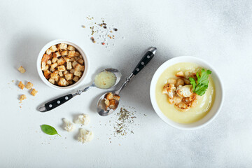 Cauliflower puree soup with croutons on white table, selective focus, top view