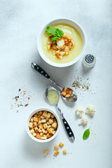 Cauliflower puree soup with croutons on white table, selective focus, top view