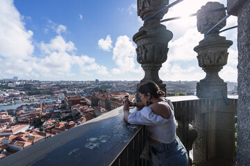 Chica joven guapa tomando fotos panoramicas desde un punto elevado en Oporto
