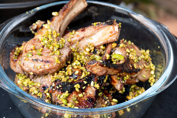 Lamb cutlets chops grilled on barbecue plate with pistachio nut . Backyard BBQ grill cooking....