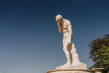 Statue making a facepalm against sky