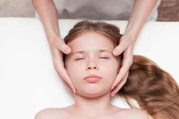 a seven-year-old girl at an appointment with an osteopath. Pediatric osteopathy. Headaches in school-age children. Correction of the skull, spine.