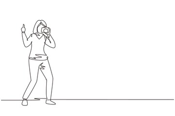 Single continuous line drawing cute woman photographer standing, thumbs up gesture, holding photo camera and photographing. Creative profession or occupation. One line draw design vector illustration