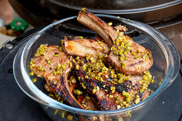 Lamb cutlets chops grilled on barbecue plate with pistachio nut . Backyard BBQ grill cooking. Australia Day celebration