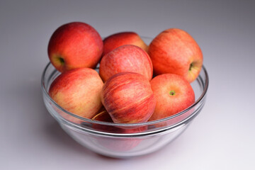 Glass bowl filled with red apples, isolated on grey background. Apples in bowl. Fresh ripe apples in bowl, selective focus.