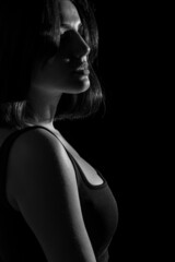 Portrait of attractive a young woman with cinematic lighting. Woman wearing a suspender bodysuit. Half naked sexy woman. Vertical shot. Dramatic monochrome, black and white photo.
