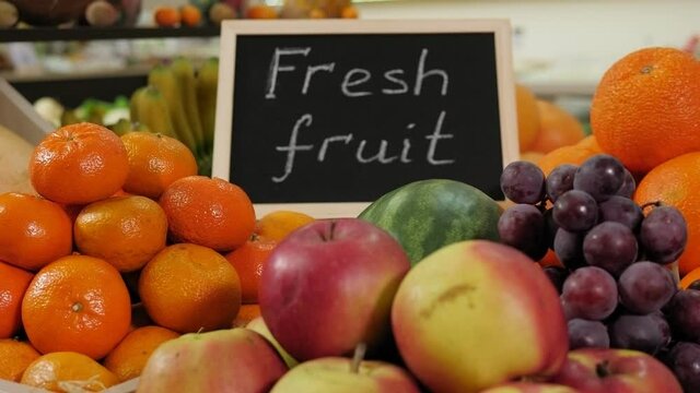 Close-up of various fruits in boxes on the shelves in a grocery store, next to there is a nameplate with the inscription FRESH FRUITS.