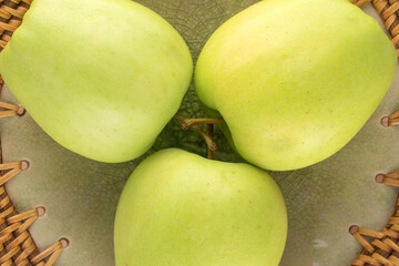 Three ripe sweet apples in a ceramic dish , close-up, top view.