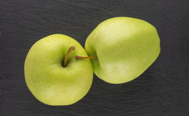 Two ripe sweet apples on a slate stone, close-up, top view.
