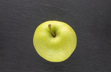 One ripe sweet apple on a slate stone, close-up, top view.