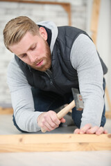 handyman installing wooden flooring in patio
