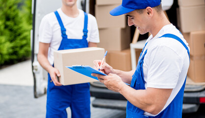 Two removal company workers unloading boxes from minibus into new home