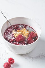 Chia pudding in bowl with raspberries, peanut butter and coconut. Vegan food concept.