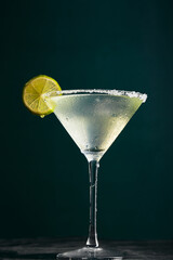 Glass of martini with cocktail or mocktail and lime wedge on dark background