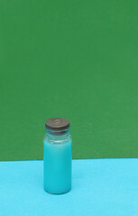 Injection bottle with medicine on blue and green background.