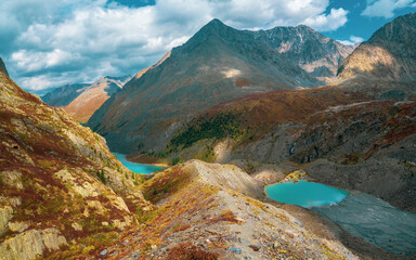 Panoramic views to motley mountain valley with lazurite lakes. Scenic mountain landscape with multicolor pointed rocks. Colorful highland scenery with sharp rocks and multicolor mountain valley.