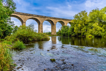 Fototapeta na wymiar A view along the River Wharfe towards the Arthington Viaduct in Yorkshire, UK in summertime
